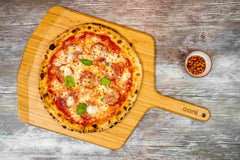 Turkey Pepperoni and Hot Honey Pizza on a wooden pizza paddle