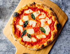 Margherita pizza on a wooden pizza peel baked using a Margherita pizza recipe.
