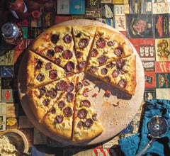 Pizza on a round wooden board with vegan pepperoni and vegan parmesan