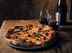 Pizza served on wooden table with red wine