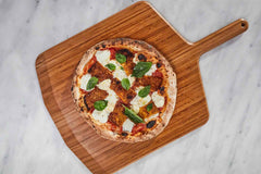 Pizza with fried eggplant, cheese, tomato sauce and basil on a bamboo serving board