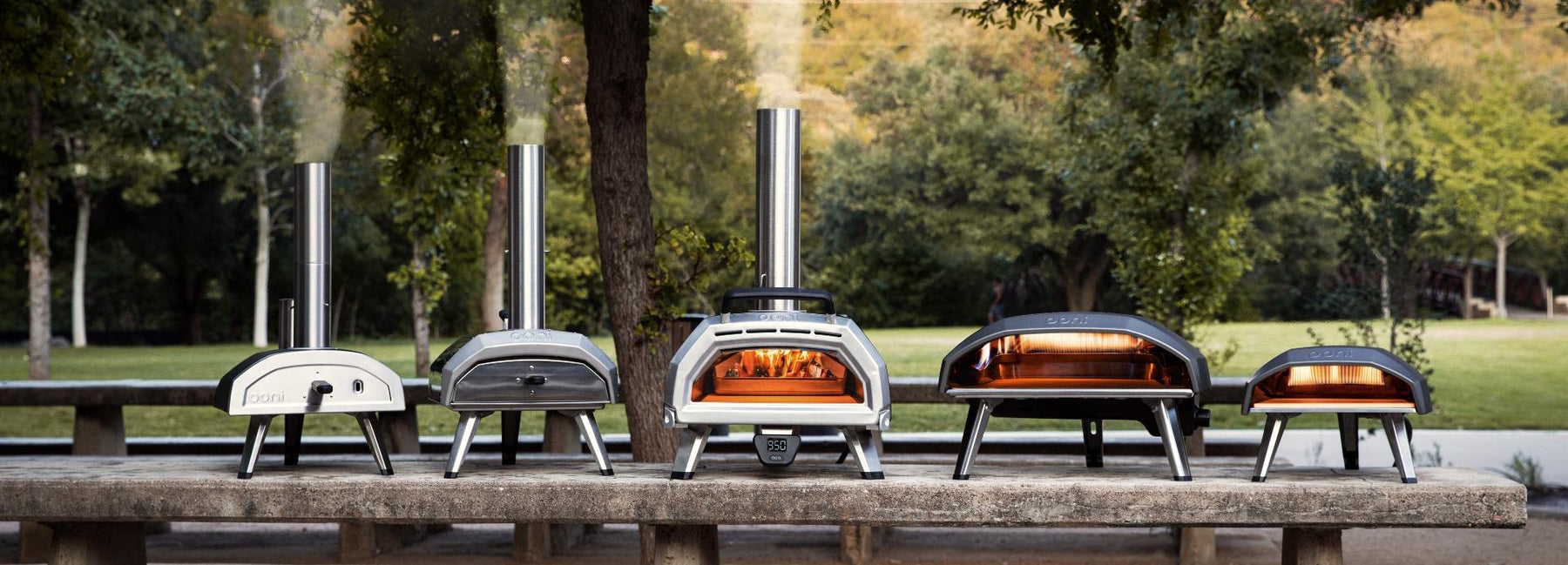 Collection of Ooni Pizza ovens on top of a wooden bench