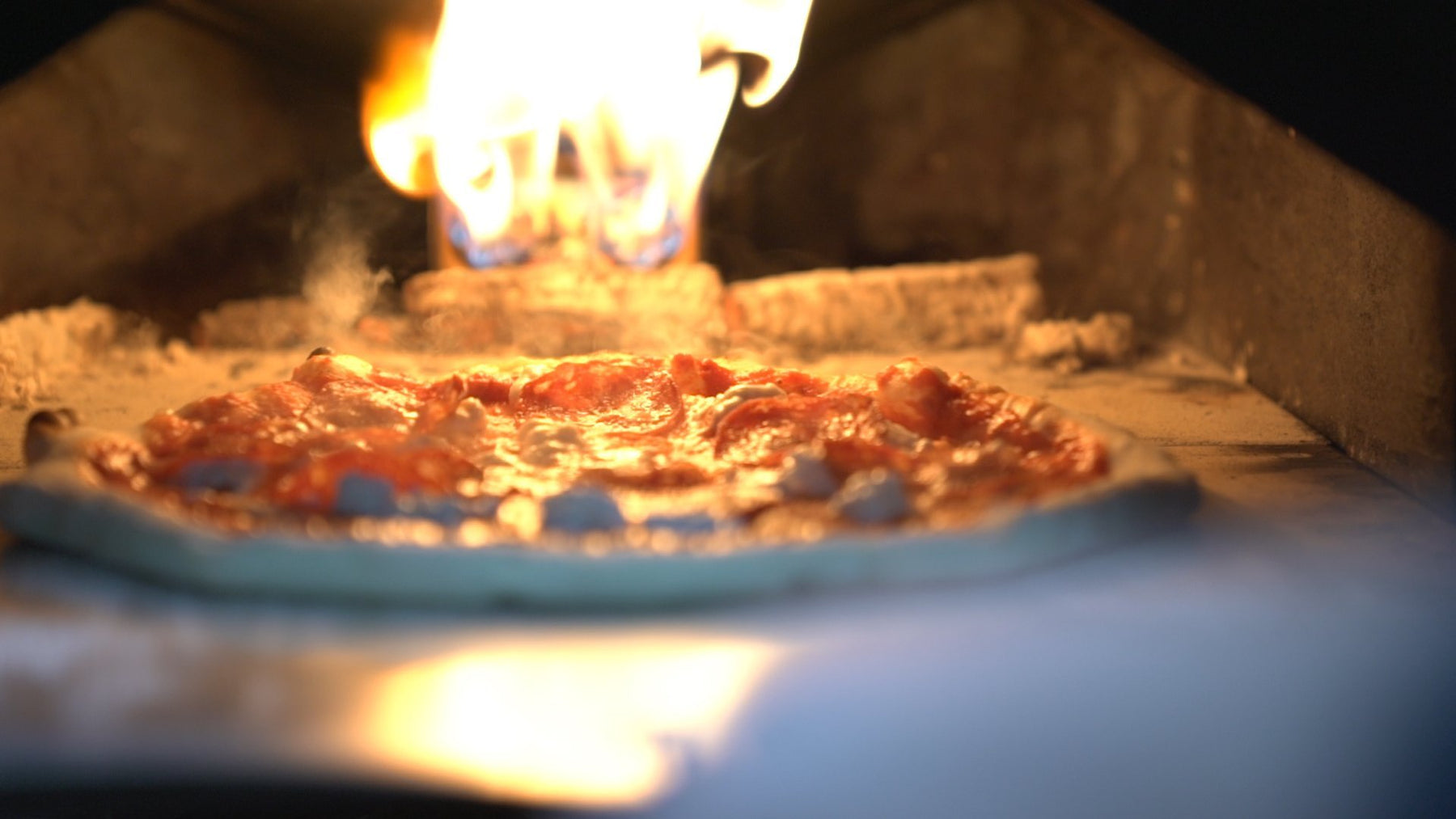 A pizza topped with haggis cooking in a pizza oven for Burns Night