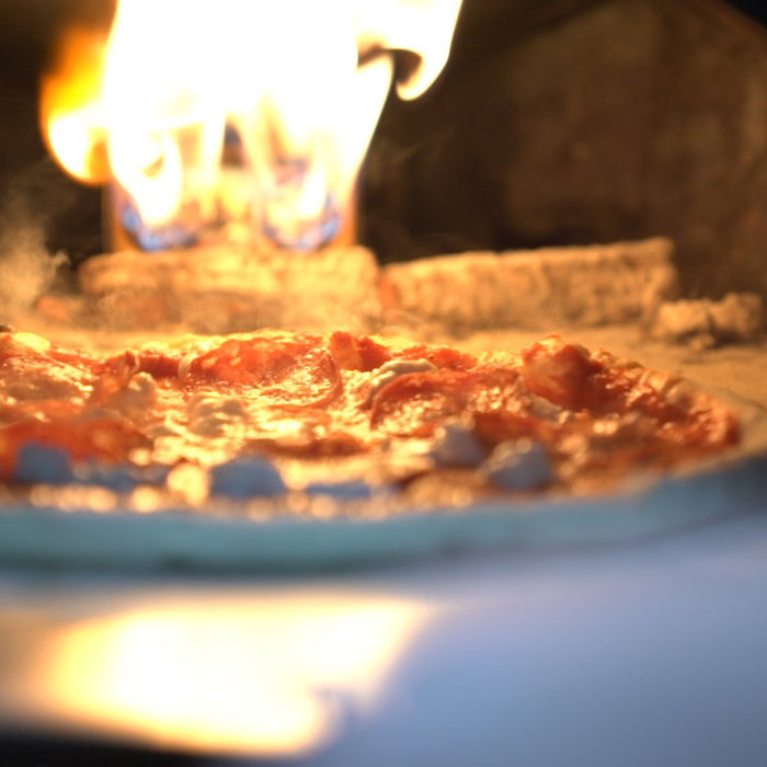 A pizza topped with haggis cooking in a pizza oven for Burns Night