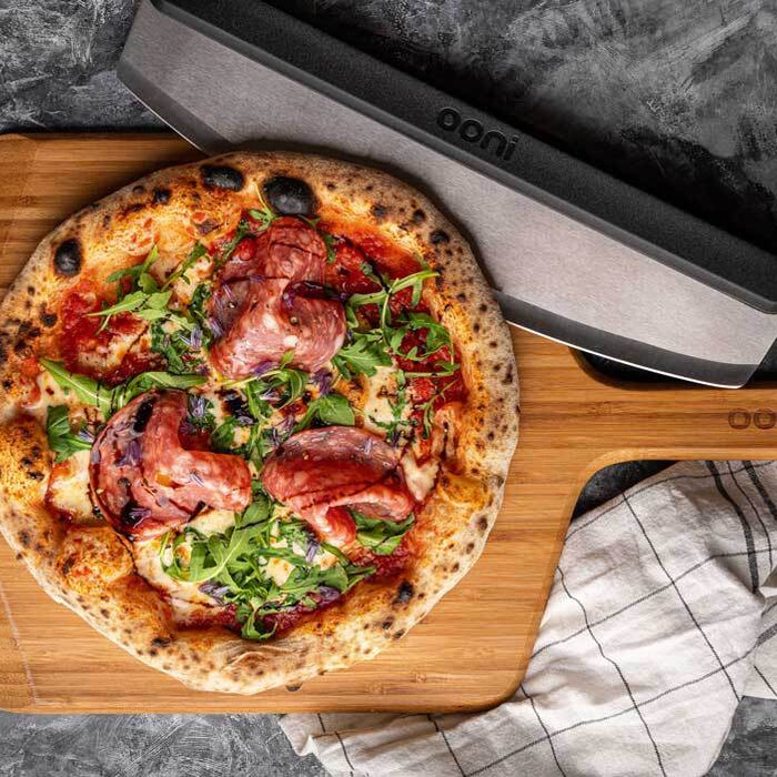 A pizza topped with rocket and salami on a wooden pizza peel, baked using a salami pizza recipe.