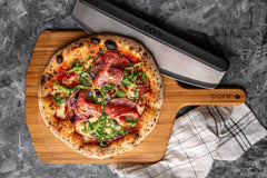 A pizza topped with rocket and salami on a wooden pizza peel, baked using a salami pizza recipe.