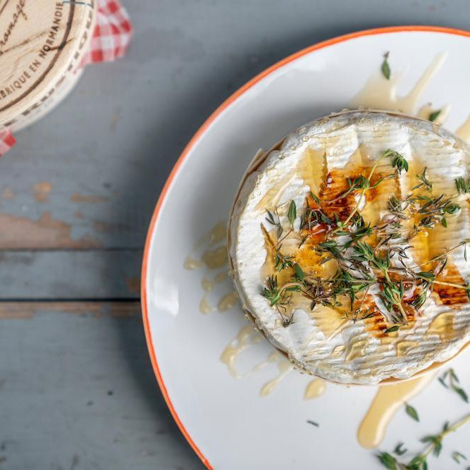 Baked Camembert topped with honey and thyme on a white plate, made using a baked camembert recipe.