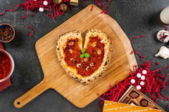 Heart shaped pizza on a wooden pizza peel