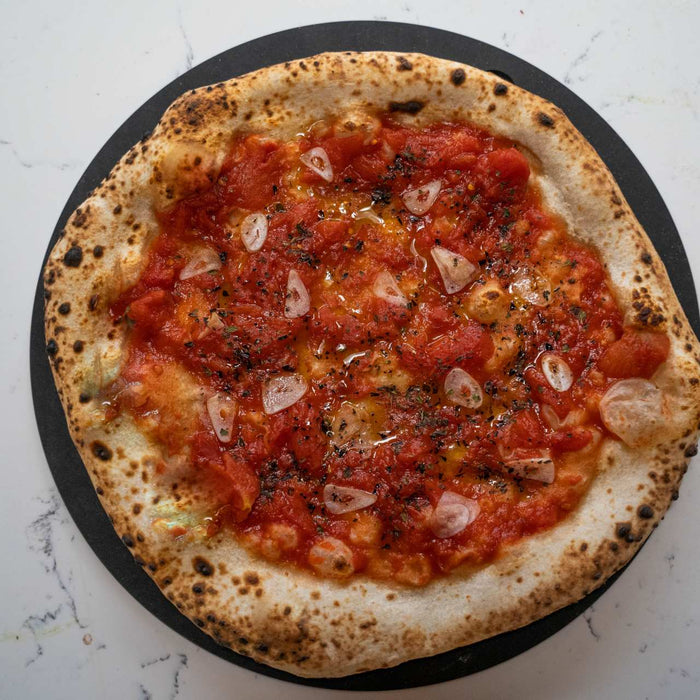 A neapolitan style pizza with tomato sauce topping