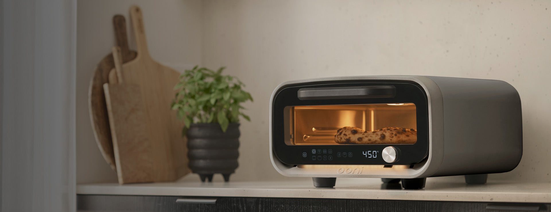 A stainless steel electric pizza oven with a glass door and front dials.