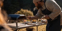 A man cooks in the koda 12 pizza oven using a cast iron skillet