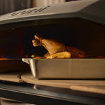 chicken cooking in Ooni roasting pan on the rotating stone 
