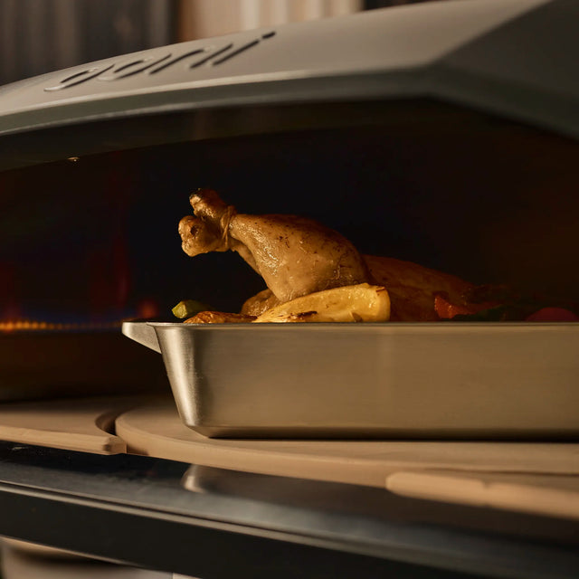 chicken cooking in Ooni roasting pan on the rotating stone 