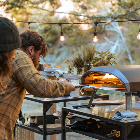 A group of friends cook pizza using the Koda 16 pizza oven