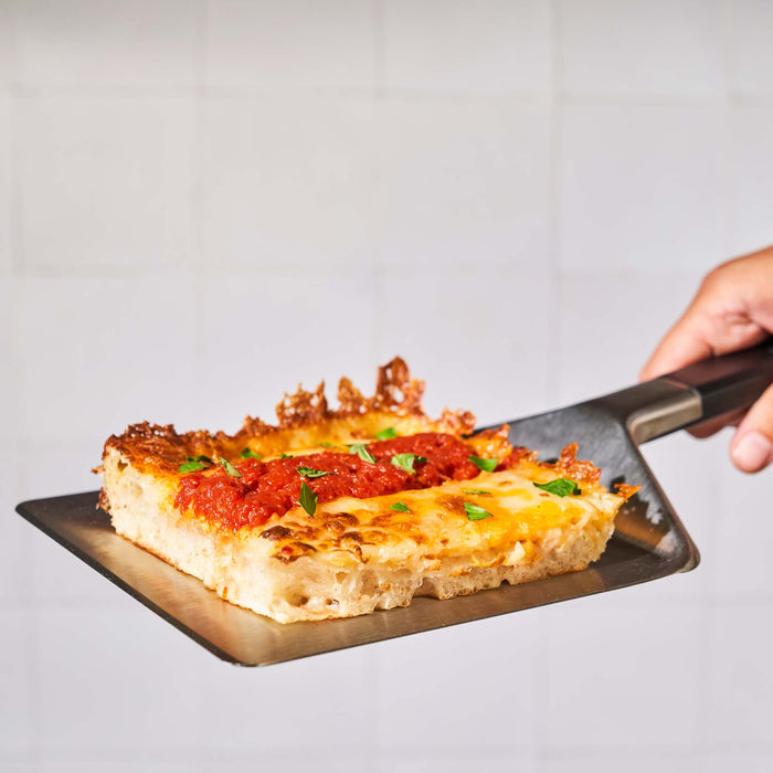 Ooni Pan Pizza Spatula holding Detroit-style pizza slice | Click this image to open up the product gallery modal. The product gallery modal allows the images to be zoomed in on.