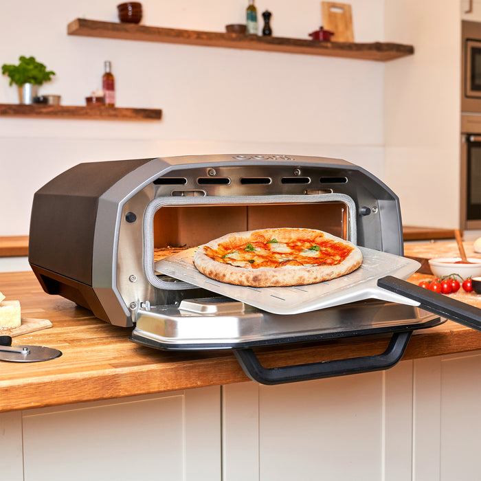 Cooked pizza on peel from Ooni Volt 12 Electric Pizza Oven | Click this image to open up the product gallery modal. The product gallery modal allows the images to be zoomed in on.
